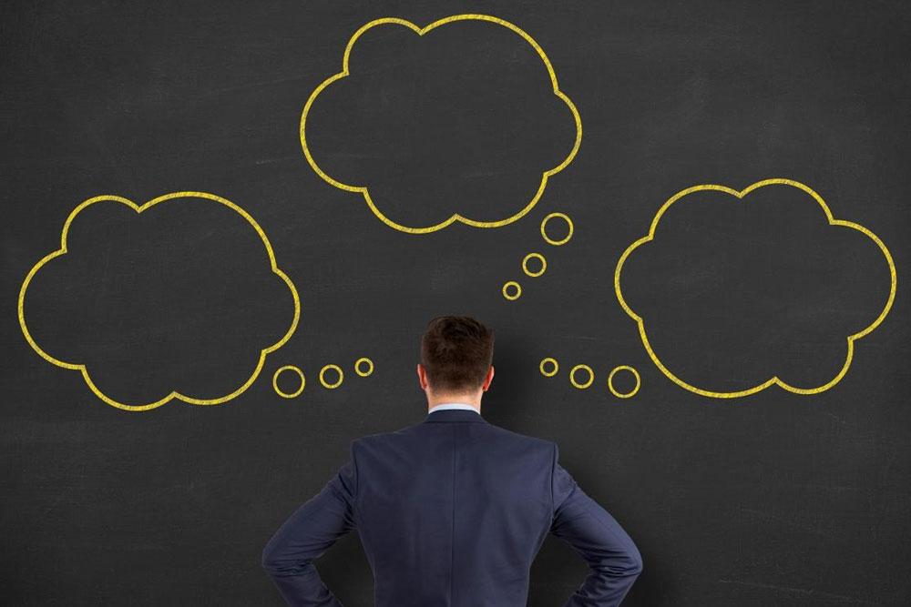 man in suit staring at blackboard with sketches on it