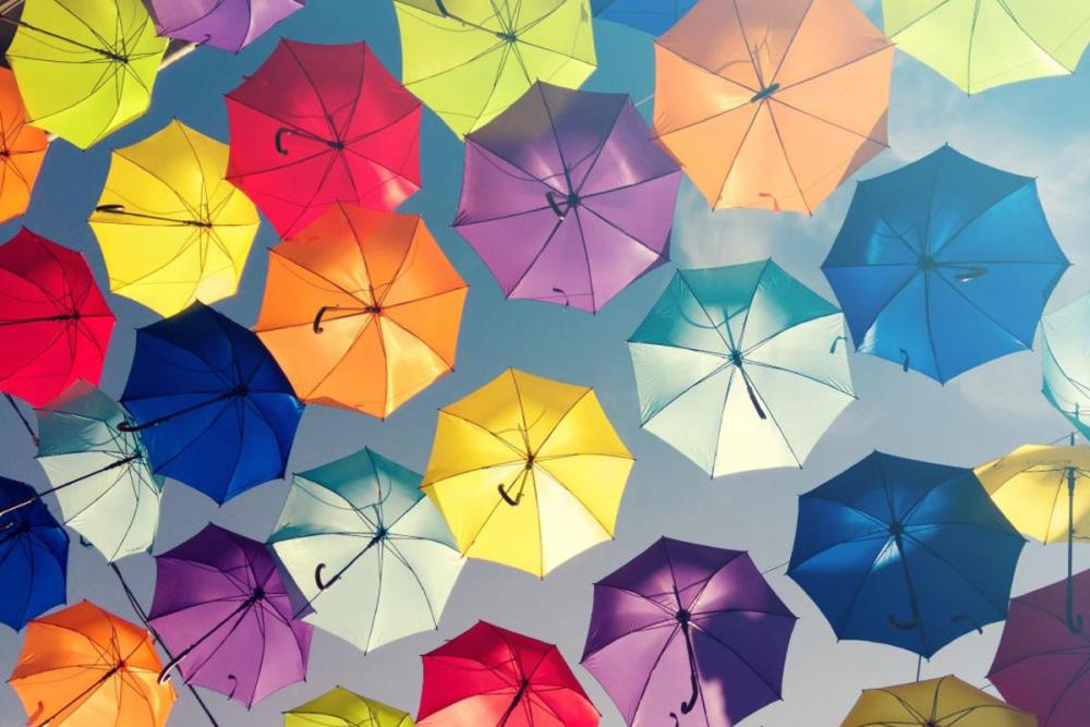 Loys of different coloured umbrellas with sky in background