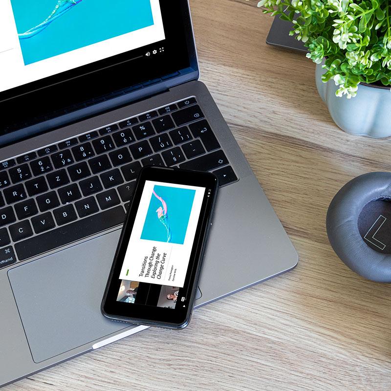 Phone and laptop with headphones on a desk