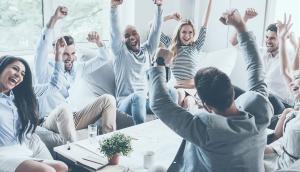 Large team in office at desks all celebrating