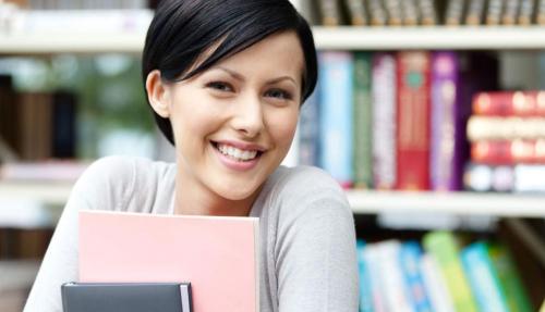 Smiling young lady with books in background at office