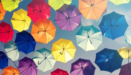 Loys of different coloured umbrellas with sky in background