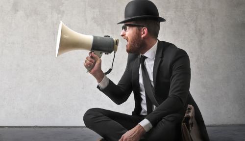 Man with suit and top hat yelling through megaphone