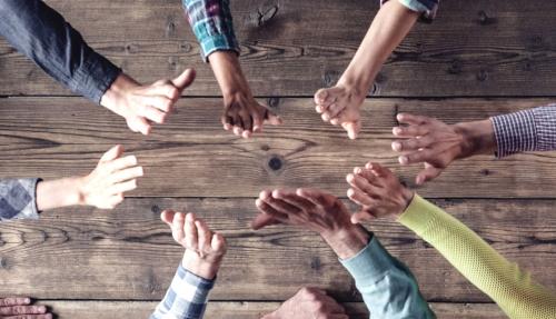 Lots of hands together on wooden table
