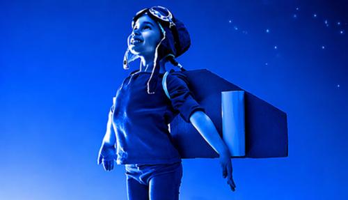 Child with wings pretending takeoff blue background
