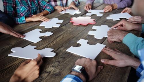 People doing large jigsaw puzzle on wooden table