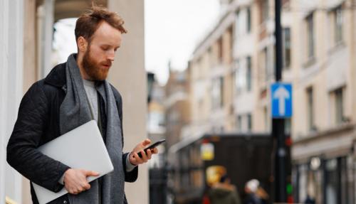 Man i backstreet with scarf on looking at phone